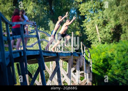 Children jump from a wooden bridge into the river Stock Photo