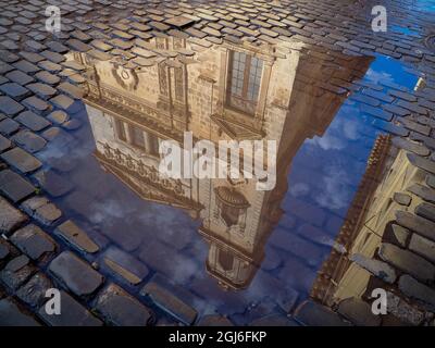 Cuba, Havana, Havana Vieja (UNESCO World Heritage Site), reflection of historic building in puddle on cobblestone street. Stock Photo