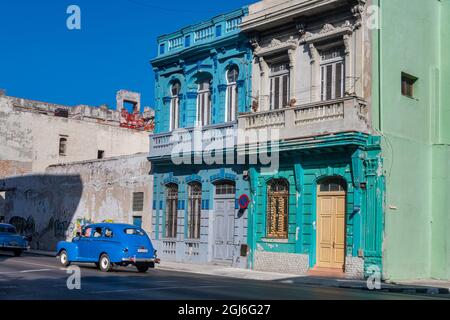 Blue classic American car parked in front of colorful crumbling buildings on street in Old Havana; La Habana, Vieja, Cuba. Stock Photo