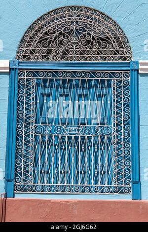 Ornate wrought iron covering on blue wooden window shutters, Trinidad, Cuba Stock Photo