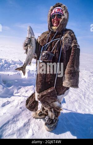 Baker Lake, Nunavut, Canada. Woman dressed in traditional caribou clothing,  tries her hand at ice fishing. (Editorial Use Only Stock Photo - Alamy