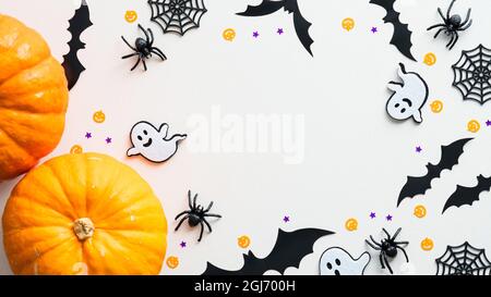Happy Halloween frame made of pumpkins, ghosts, bats, spiders, web on white background. Flat lay, top view, copy space. Halloween banner mockup. Stock Photo