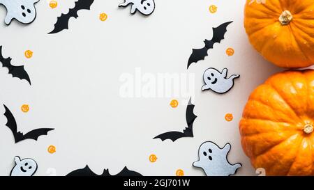 Halloween background with cute decorations and pumpkins on white table. Flat lay, top view, copy space. Halloween party invitation card mockup. Stock Photo