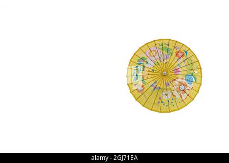Top view of an open yellow oriental paper umbrella with blue, green, red, purple, orange and brown flower and leaf decoration on a white studio backgr Stock Photo