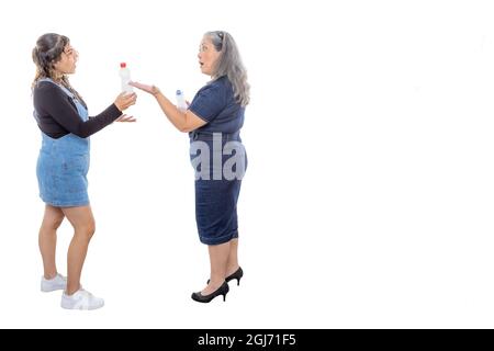 Mature mother explaining to her teenage daughter the importance of environmental awareness, two women with plastic bottles, light makeup, casual style Stock Photo