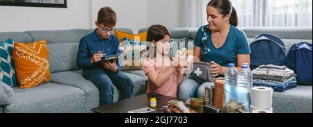 Mother preparing emergency backpack with her children Stock Photo