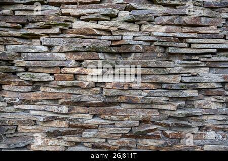 The masonry wall is made of flat stones. Stock Photo