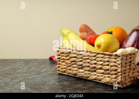 Basket with vegetables and fruits on kitchen towel on black smokey table Stock Photo