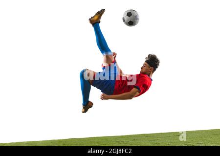 Horizontal portrait of young sportsman, soccer football player in motion kicking a ball isolated over white background Stock Photo