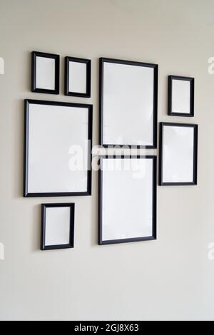 Different size framed photos hanging on the gray wall. Mockup. Stock Photo