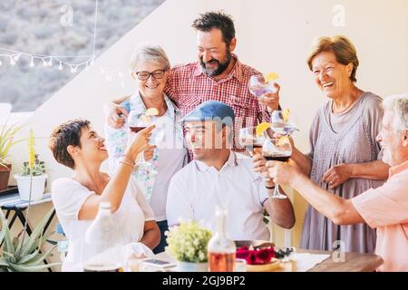 Multi generation caucasian family toasting wine glasses and celebrating a get together at open terrace of house. Loving family drinking wine and enjoy Stock Photo