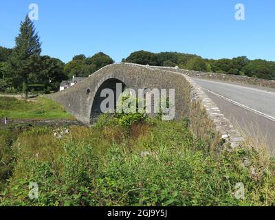 The single-arched, hump-backed Clachan Bridge is known as 'The Bridge over the Atlantic', connecting the Scottish mainland to the Isle of Seil. Stock Photo