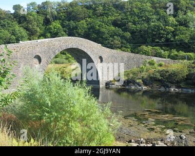 The single-arched, hump-backed Clachan Bridge is known as 'The Bridge over the Atlantic', connecting the Scottish mainland to the Isle of Seil. Stock Photo