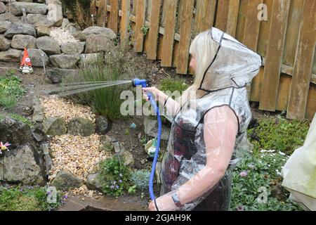 White caucasian woman aged 64 wears a clear plastic raincoat Stock Photo