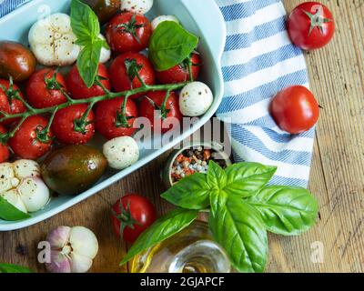 Fresh vegetable tomato, basil, mozzarella cheese for baking in the oven in ceramic dishes. cooking. Stock Photo