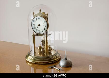 antique clock in glass dome, with oil pot and crown. Selective Focus Object. Stock Photo