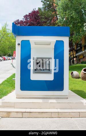 With one cash machine, ATM, dustbin and security camera in the park. Blue Stock Photo