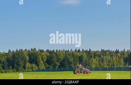 Summer landscape. The tractor is driving through a mown field.  Stock Photo