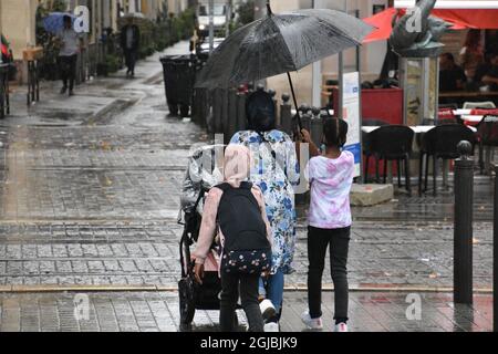 Marseille, France. 3rd Sep, 2021. A child walks along the streets of Marseille sheltering her mother with an umbrella on a rainy day. (Credit Image: © Gerard Bottino/SOPA Images via ZUMA Press Wire) Stock Photo