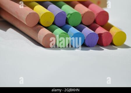 Coloured chalks arranged on a white background. Stock Photo