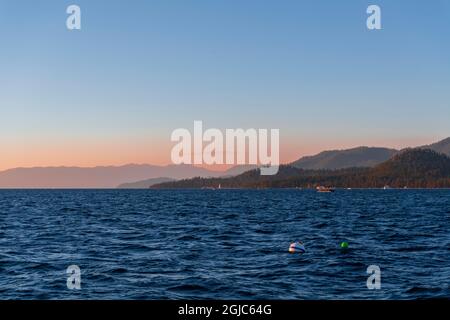The deep blue waters of Lake Tahoe with sunset colors over the mountains Stock Photo