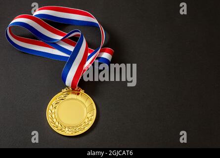 Number one gold medal. Champion first place winner athlete. Prize in sport trophy award and red and blue ribbon isolated on white background. Blank sp Stock Photo