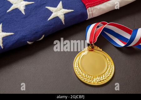 Medal gold for USA. Winner prize award with ribbon and US flag on black background. American athlete trophy in sport for first place champion. Blank s Stock Photo