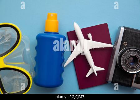 Overhead view of essential holiday travel items with a toy airplane on a blue background Stock Photo
