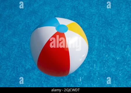 Inflatable beach ball floating in swimming pool Stock Photo