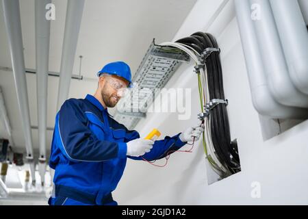 Electrician Doing Cable Installation And Maintenance In Office Stock Photo