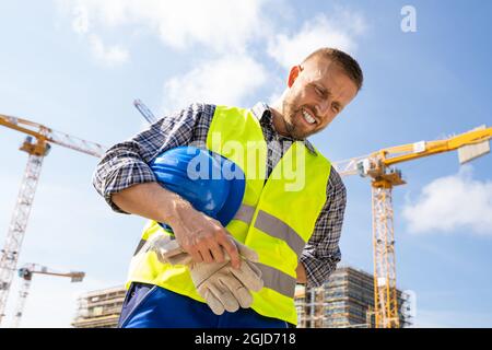 Engineer With Back Pain Injury After Accident At Construction Site Stock Photo