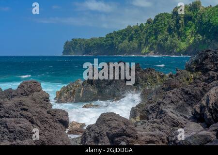 USA, Hawaii, Big Island of Hawaii. Laupahoehoe Point Beach Park, Volcanic rock, incoming waves and distant tropical forest. Stock Photo
