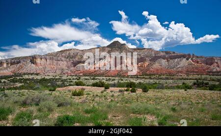 USA, New Mexico. White clouds in a blue sky over colorful sandstone cliffs. Stock Photo