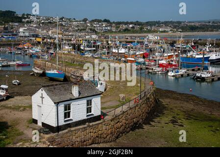 Newlyn, Cornwall, England, UK. 2021, A seaman's chapel on the old harbour wall with a background of the fishing fleet in Newlyn Harbour the largest fi Stock Photo
