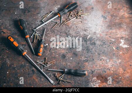 Screwdrivers and screws on a wooden workbench. Top view on working tools with space for text. Construction tools on work wooden table. Background. Stock Photo
