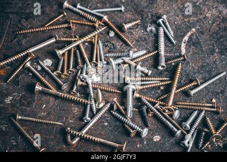 A lot of screws on wood workbench. Different Kind of Screws on a table in a workshop. Set of screws. Construction abstraction. Industrial background. Stock Photo