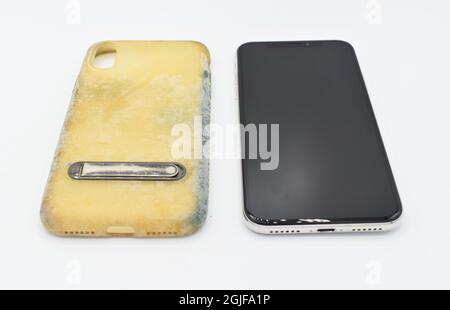 New smartphone, and old and dirty silicon phone case due to yellow stains and mold. Isolated on white background. Stock Photo