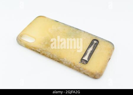 Old and dirty silicon phone case due to yellow stains and mold. Isolated on white background. Stock Photo