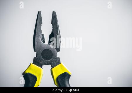Yellow pliers on white background. New pliers with yellow and black grip isolated on white background. Top view. Repair or building tools. Stock Photo