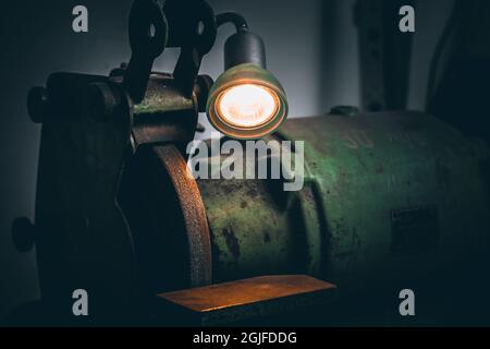 Green Electrical grinding machine. Industrial Bench Grinder in workshop. Close up on bench grinding machine with light. Stock Photo