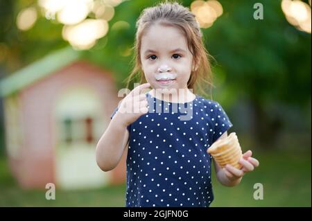 Portrait of girl with ice cream in hand on blurred park background Stock Photo