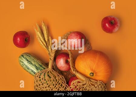 Cotton mesh bag with fresh colorful fruits and vegetables on orange background. Shopping and healthy lifestyle concept. Zero waste concept. Creative flat lay with place for text. Stock Photo