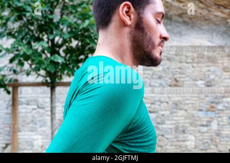 Young Caucasian bearded man wearing a green shirt and walking in a park Stock Photo