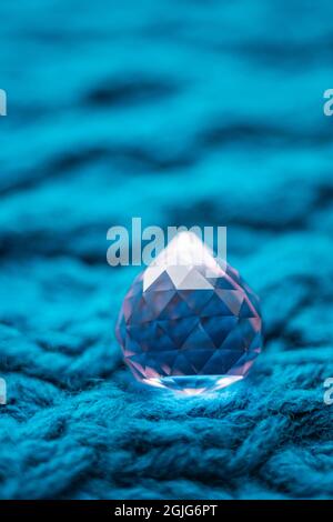 Large pink crystal on a pale blue knitted table. Stock Photo