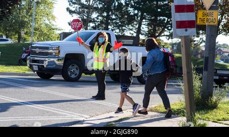Mississauga, Canada. 9th Sep, 2021. A crossing guard wearing a face mask works on a street outside a school in Mississauga, the Greater Toronto Area, Ontario, Canada, on Sept. 9, 2021. Schools in Toronto, Peel, York and Durham started their school years on Thursday, offering a mix of in-person classes and online learning for students. Credit: Zou Zheng/Xinhua/Alamy Live News Stock Photo