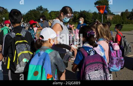 Mississauga, Canada. 9th Sep, 2021. A teacher wearing a face mask and goggles sanitizes students' hands at a school in Mississauga, the Greater Toronto Area, Ontario, Canada, on Sept. 9, 2021. Schools in Toronto, Peel, York and Durham started their school years on Thursday, offering a mix of in-person classes and online learning for students. Credit: Zou Zheng/Xinhua/Alamy Live News Stock Photo