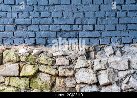 Facade of a city building with a wall from stone and blue-painted brick Stock Photo
