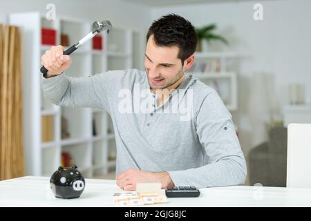 mans hand holding hammer with piggy bank Stock Photo