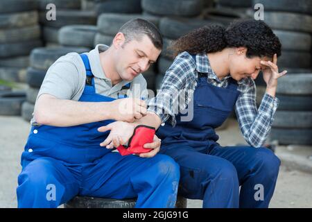 repairman helping female colleague with wrist in pain Stock Photo