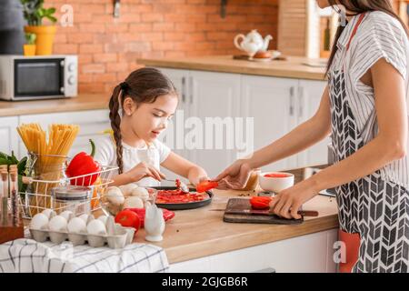 Young mother and daughter cooking pizza in kitchen at home Stock Photo